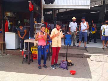 2 people singing outside a marketplace. Some people are around