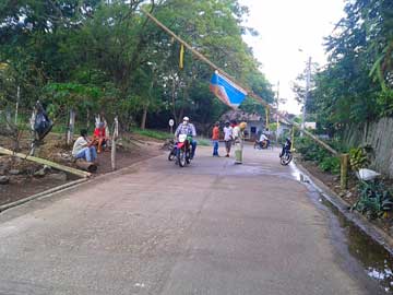 Some guys at a checkpoint. One of them is spraying a motorcycle