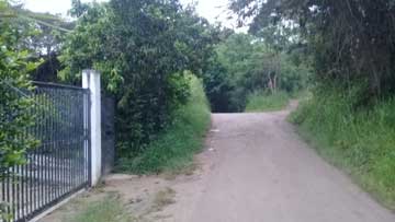 An intersection of 2 roads. An entrance gate is on the roadside