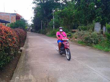 A guy with a mask, driving a motorcycle on a lonely street