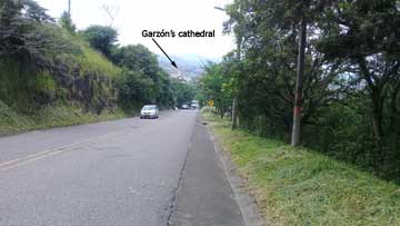 A road that runs downhill. In the distance, part of the town of Garzón