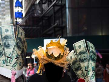 A golden king's crown on top of a pile of straw and 2 bundles of one-hundred-dollar bills: one on the left and the other on the right