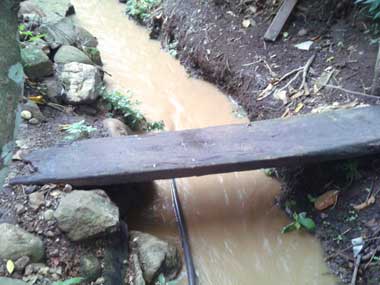 An orange or beige  water stream and a wooden bridge